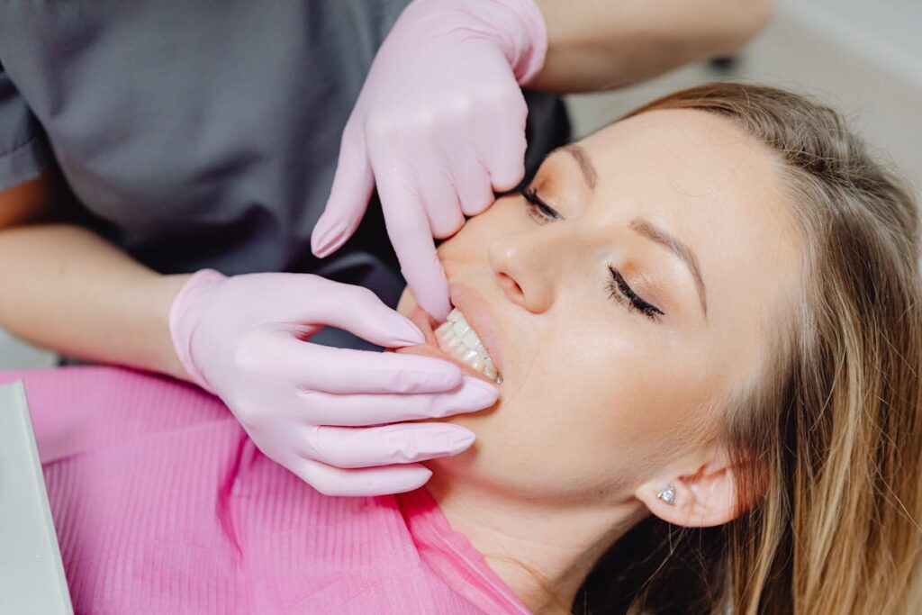 A Person Wearing Latex Gloves Checking a Woman's Teeth