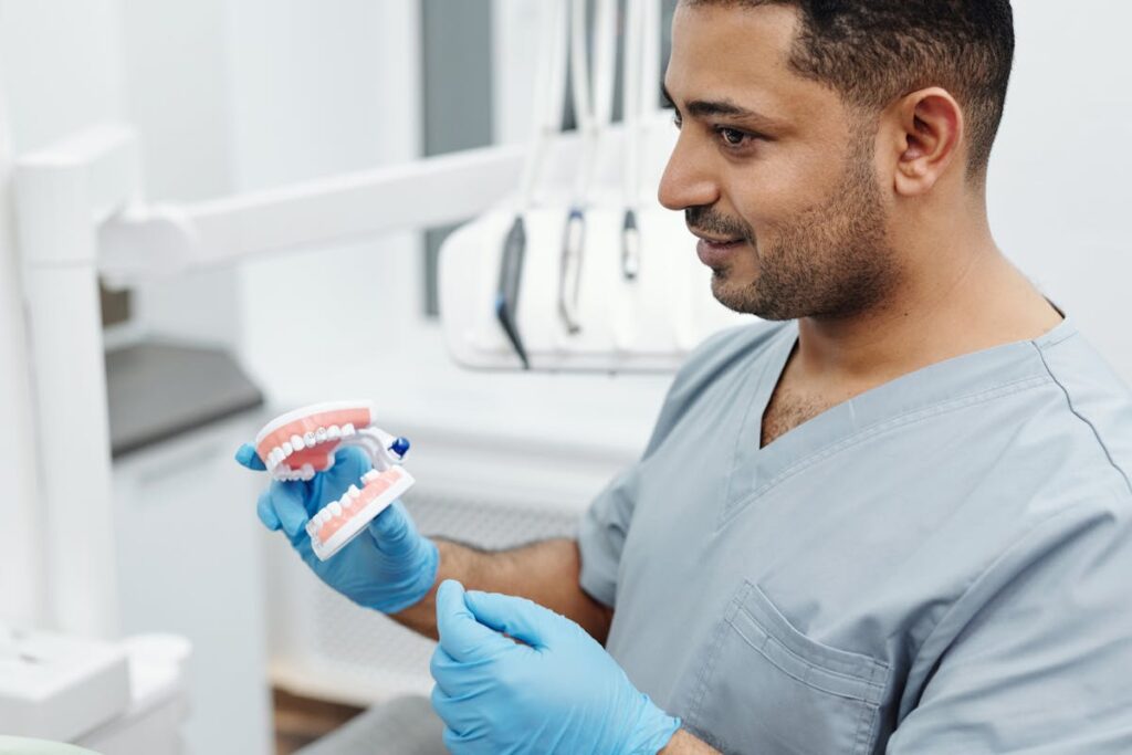 Man in gray Scrub Suit Holding Teeth Model