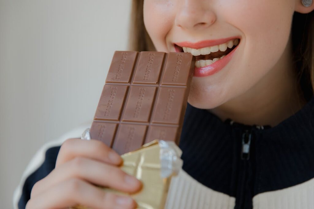 Woman Biting a Brown Chocolate Bar