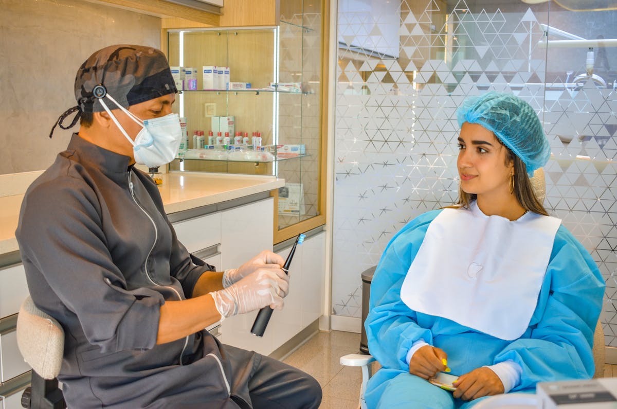 Dentist Sitting Beside a Patient with an Electric Toothbrush