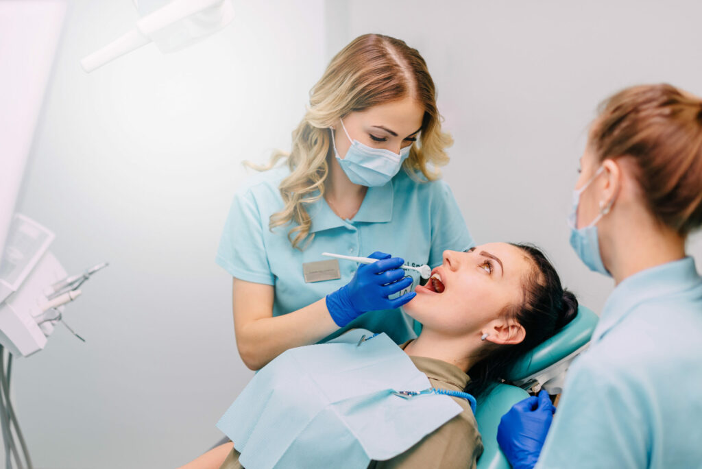 young woman dentist performs examination of patient in clinic
