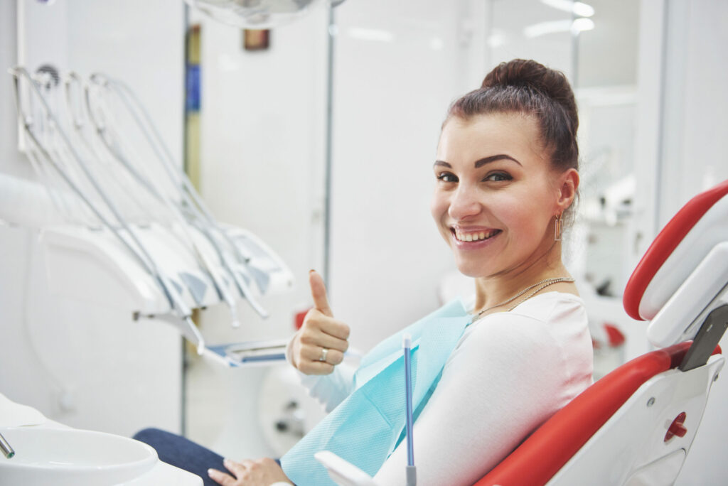 Satisfied patient showing her perfect smile after treatment in a dentist clinic.