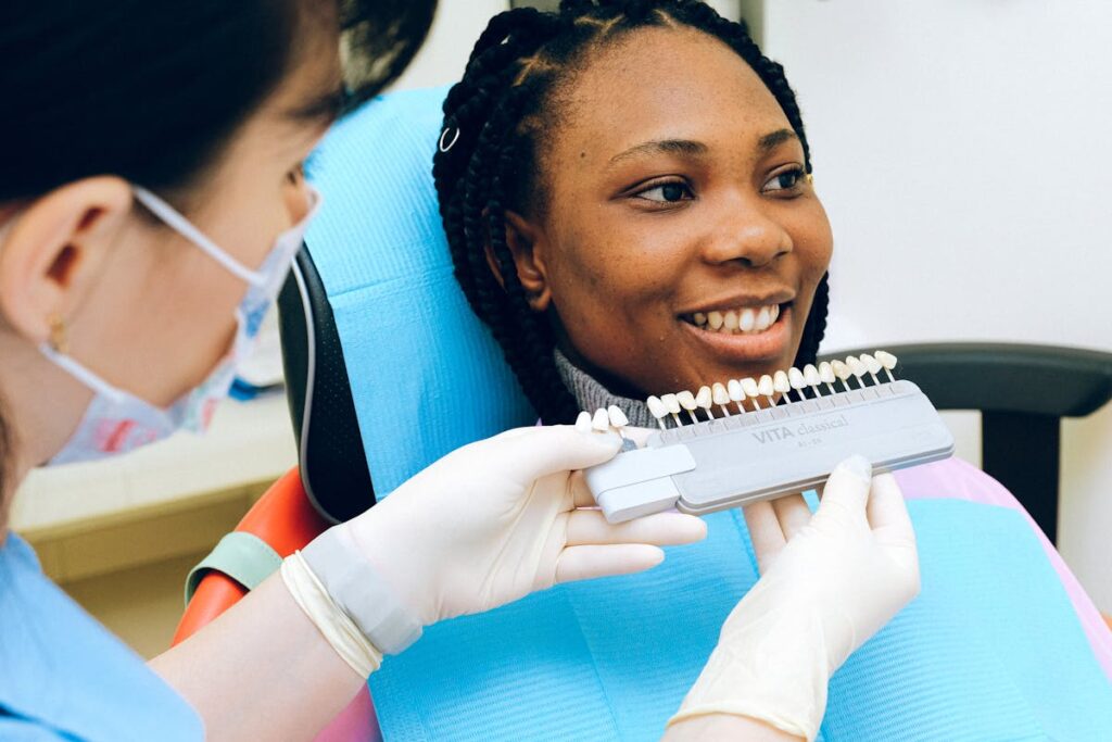 A dentist conducts a dental shade matching procedure with a smiling patient in the clinic.