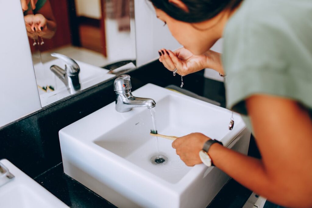Woman brushes teeth at modern sink. Focus on hygiene and daily routine.