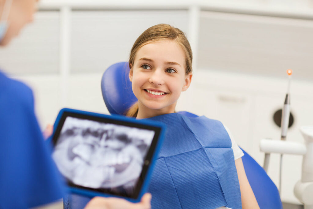 people, medicine, stomatology, technology and health care concept - dentist with x-ray on tablet pc computer and girl patient